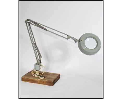 A vintage 20th Century industrial illuminated magnifying optic, raised on an&nbsp;standing anglepoise frame mounted on a wood