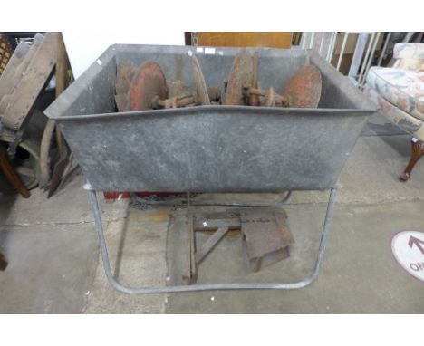 A galvanised trough on stand and agricultural tool implements 