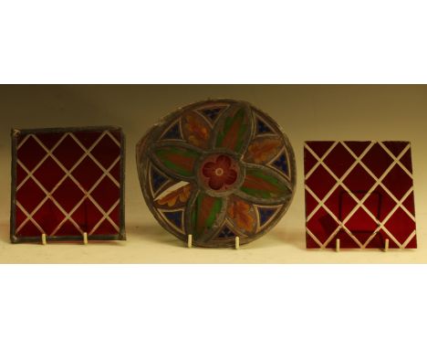 A 19th century stained glass roundel, painted with a flower and stiff leaves, 18cm diam, c.1860; ruby glass panels (3) 