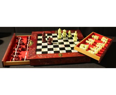A Chinese style chess set and folding storage board, cast resin pieces, the case carved and engraved, brass mounted, sliding 