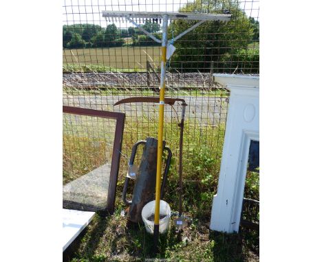 A rake, post knocker, bucket, staples and a scythe.