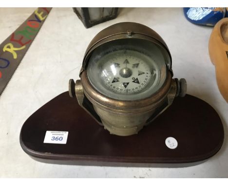 A BRASS SHIPS COMPASS ON A WOODEN BASE 