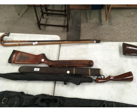 THREE ITEMS - AN UNUSUAL UMBRELLA WITH GUN STOCK STYLE HANDLE, AN AIR RIFLE STOCK AND A BRASS BANDED CARVED HARDWOOD SCABBARD