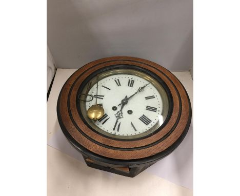 A VINTAGE OAK FRAMED ENAMEL FACED SCHOOL/STATION CLOCK WITH KEY AND PENDULUM DIAMETER 40CM 