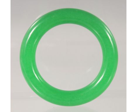 A CHINESE GREEN JADE BANGLE 8.5cm diameter.