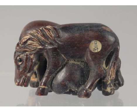 A CARVED WOOD NETSUKE modelled as horses. 4.5cm long.