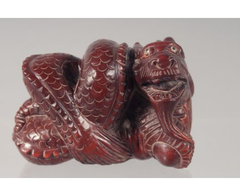 A CARVED WOOD NETSUKE modelled as a dragon 5.5cm long.