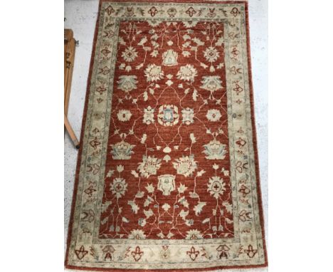 A Cholie rug, the central panel set with all over scrolling foliate decoration on a terracotta ground within a stepped beige 