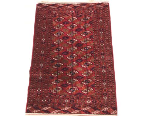 A Bokhara Tekke rug, the central panel set with three rows of elephant foot medallions interspersed with diamond decoration o
