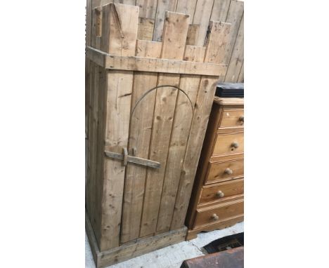 A modern pine wardrobe in the Medieval style with castellated top over a domed door with simple wooden latch lock, raised on 