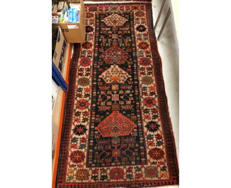 A Caucasian rug, the central panel set with repeating floral decorated medallions on a black ground with stylised animal moti