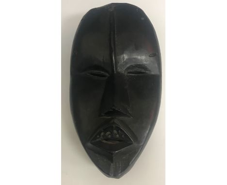 A modern carved “Black” stone mask 21 cm high together with a 20th Century African carved panel decorated with figures workin