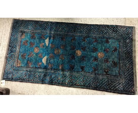 A vintage Chinese rug, the central panel set with repeating stylised frog motif and roundels on a blue ground, within a stepp