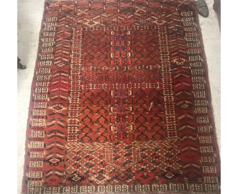 A Hatchli Bokhara rug, the central panel set with black design on a red ground within a stepped red, blue and cream geometric