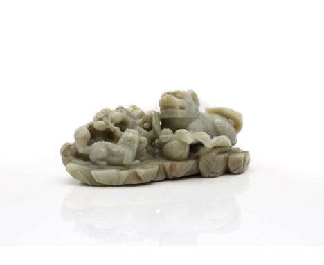 A Chinese jade carving, 20th century, of a Buddhist lion and a pup playing with a brocade ball by a rock,24cm longCondition R