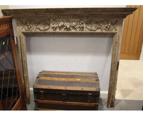 A George III pine fire surround frieze having central panel carved fruit flanked by scrolls, decorative carved border to open