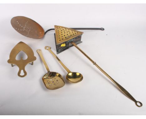 A 19th Century brass chestnut roaster, a brass cream skimmer, a ladle, a pierced spoon and a trivet