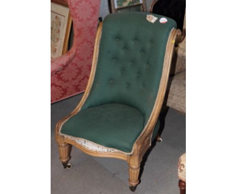 A Victorian nursing chair, button upholstered in a green fabric, with scroll carved side rails