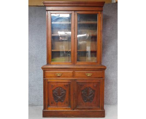 A late Victorian carved walnut library bookcase the upper glazed section above panel doors on plinth base. H.220 W.122 D.45cm