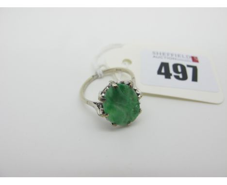 A Carved Oval Jade Panel Ring, claw set between plain shoulders, stamped "9ct" (finger size P). 