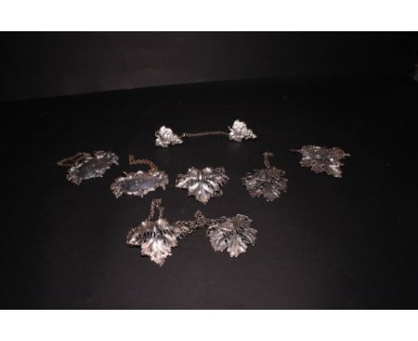 Two pairs of silver leaf-shaped decanter labels, another similar and a pair of plated decanter labels