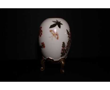 A Royal Worcester china pot-pourri vase in the form of an egg on three supports, decorated oriental flowers and butterflies a