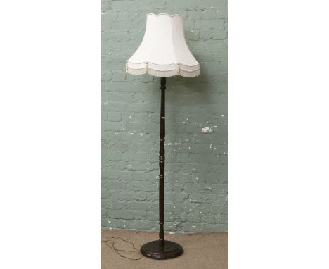 A turned mahogany standard lamp with cream shade.