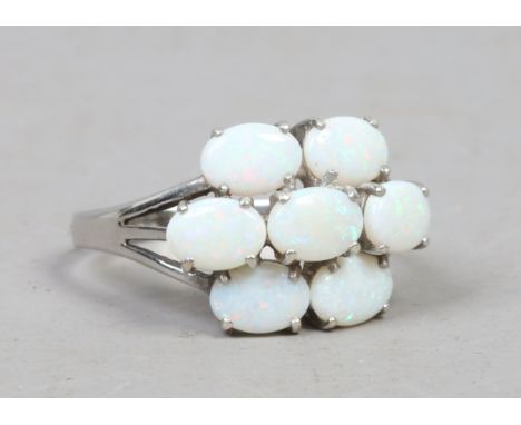 A 9ct white gold seven stone opal cluster ring set on split shoulders, size U.