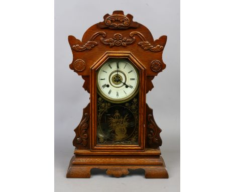 A late C19th oak cased New Haven ginger bread clock housing a two train striking alarm movement, striking on a coiled gong an