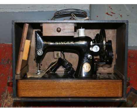 A cased vintage ornate Singer sewing machine with original instructions, packs of needles etc.