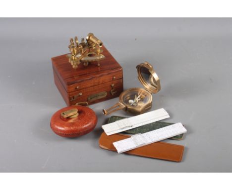 A brass miniature sextant, in case, a brass compass, a fabric tape measure and two slide rules, in leather cases 