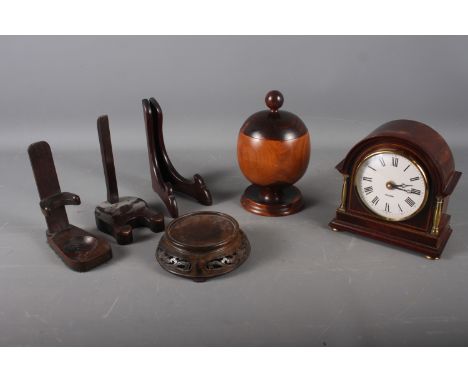 A lignum vitae jar and cover, 7" high, a Mercedes mahogany cased electric mantel clock, three plate stands and a carved hardw