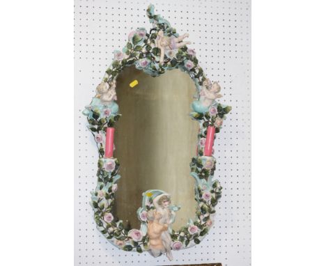 An early 20th century Dresden porcelain framed wall mirror, decorated roses, cherubs and merman, with two candle sconces, 29"