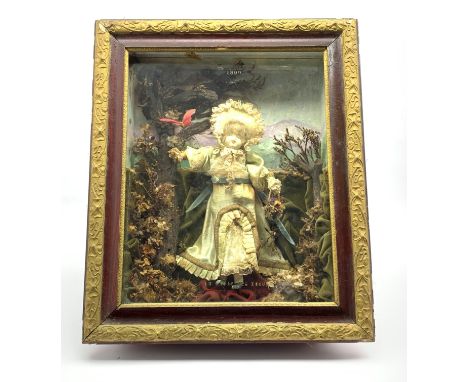 Cased clockwork automaton doll wearing a silk dress in a naturalistic garden setting, with paper label to the back of the cas