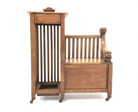 Early 20th century medium oak hall seat with carved mask decoration, hinged storage compartment, flanked by stick stand, rais