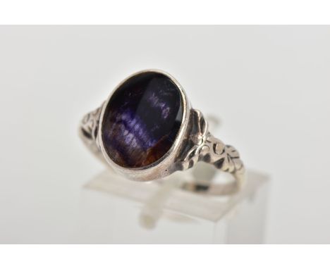 A WHITE METAL BLUE JOHN FLUORUTE RING, of an oval form set with a Blue John fluorite cabochon, collet mounted, bow detailed s