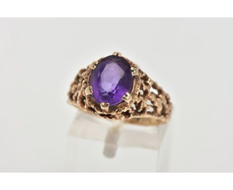AN AMETHYST DRESS RING, designed with a six claw set, oval cut amethyst, textured openwork detailed shoulders, plain polished