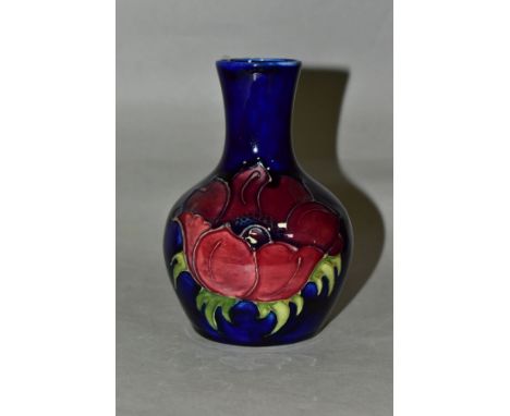 A MOORCROFT POTTERY BOTTLE SHAPED VASE DECORATED WITH RED/MAUVE ANEMONE ON A BLUE GROUND, impressed marks, height 12.5cm (Con