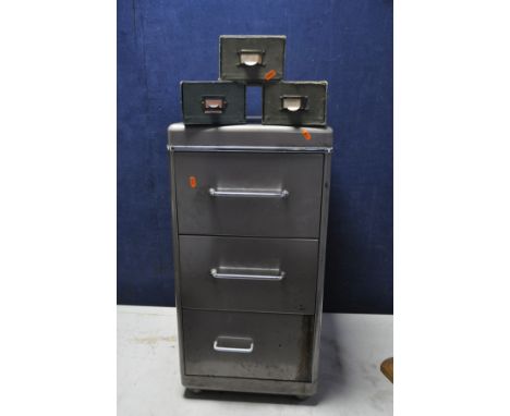 A METAL THREE DRAW FILING CABINET along with three cardboard organizers a vintage hole punch and a Essex stapler (drawers ope