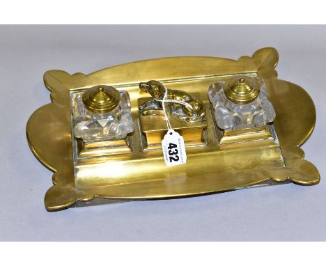 A BRASS TWIN INKWELL DESK STAND, having scalloped edges, two square glass inkwells with brass covers (one with old stapled re