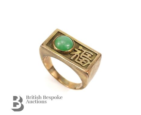 An Asian 14ct yellow gold jade ring, the ring set with a cabochon jade measuring approx. 8mm with character marks to side, si