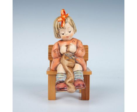 This porcelain figurine is hand-painted and finished in matte. Depicts a young girl sitting on a wooden bench. Goebel backsta