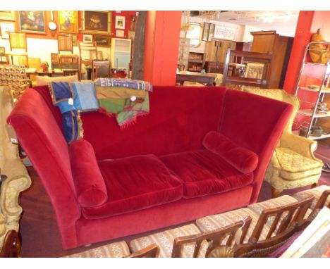 A Conran three seater sofa with red velvet upholstery and raised on bun feet. 