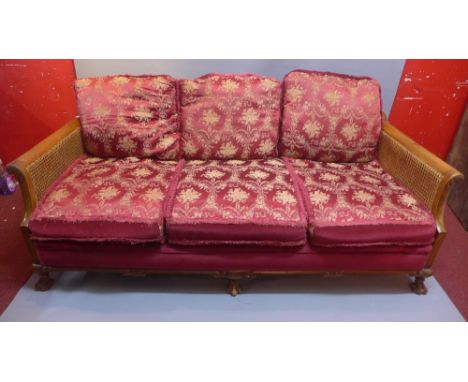 A late 19th century walnut bergere three seater sofa with floral upholstery having double caned sides and raised on scalloped