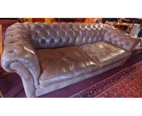 A brown leather three seater chesterfield sofa raised on bun feet