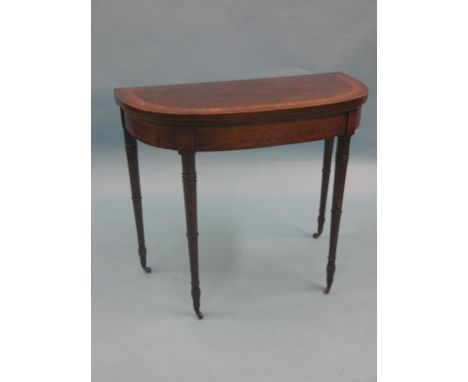 A Sheraton-period mahogany card table, half-round shape with broad satinwood cross banding, on slim, turned legs with casters