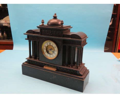 A large black slate mantel clock, architectural form with five columns to each side, enamelled chapter ring, French movement 