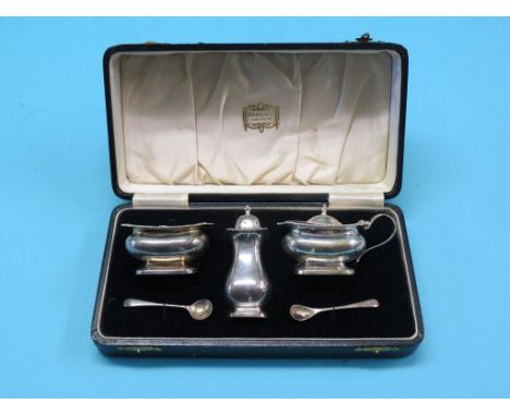 A cased silver condiment set retailed by Harrods, salt, mustard, each with blue glass liner, and pepper pot, one silver serve