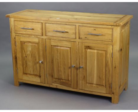 A light oak sideboard fitted three frieze drawers above cupboards enclosed by three fielded panel doors, 54” wide x 35” high 