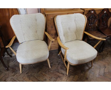 A pair of mid Century blonde Ercol teak armchairs with cream cushion upholstery 